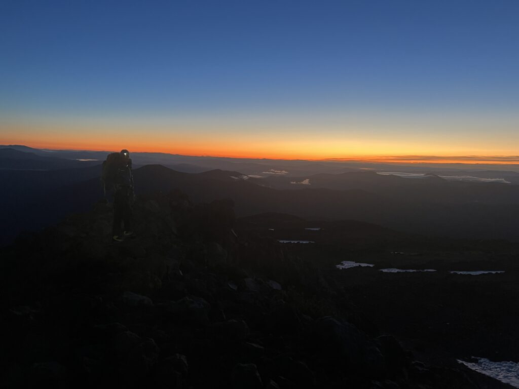 A photo of a climber at sunrise on the lower lateral moraine of Mt Shasta's Hotlum Bolam Ridge.